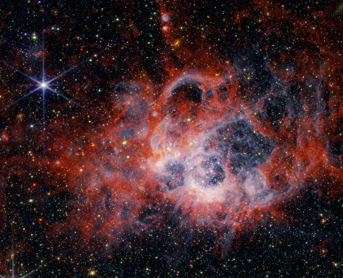 This image from NASA’s James Webb Space Telescope’s NIRCam (Near-Infrared Camera) of star-forming region NGC 604 shows how stellar winds from bright, hot young stars carve out cavities in surrounding gas and dust.