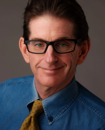 Professional headshot of man in dark rimmed glasses wearing business attire