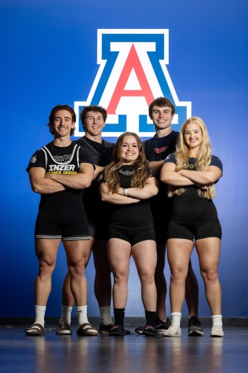 A photograph of three men and two women standing proudly with their arms crossed representing the powerlifting team in front of a UArizona Block A
