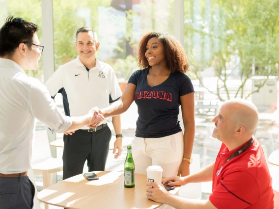 Four people smiling while they shake hands.