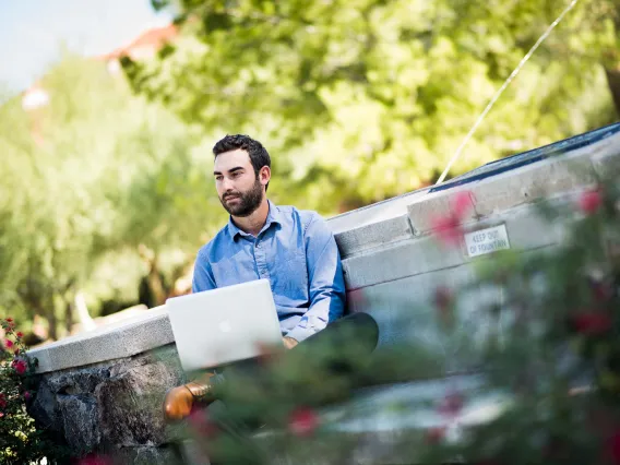 Person working on laptop in front of a fountain. 