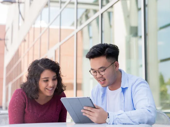 Two people sitting down looking at a tablet.