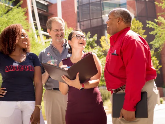 A group of 4 people standing and laughing.