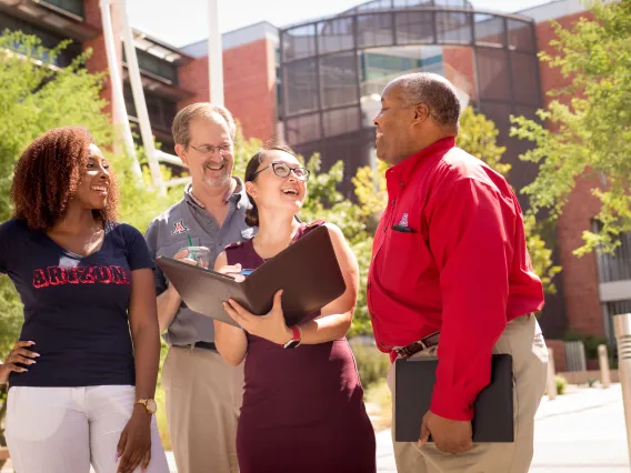 A group of 4 people standing and laughing.