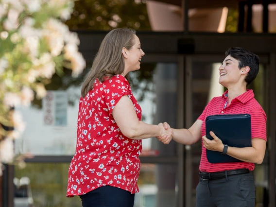 Two people greeting each other and shaking hands.