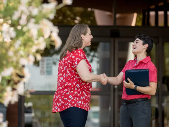 Two people greeting each other and shaking hands.