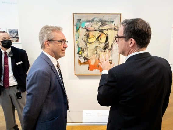 Two men talking in front of painting