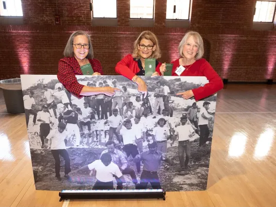 Reunion attendees holding photo of themselves from 1972