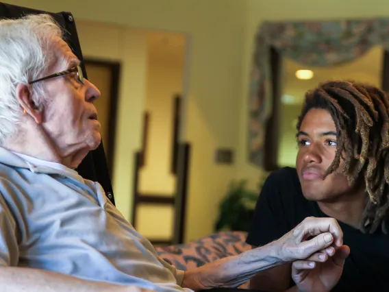 Young man speaks with elderly man