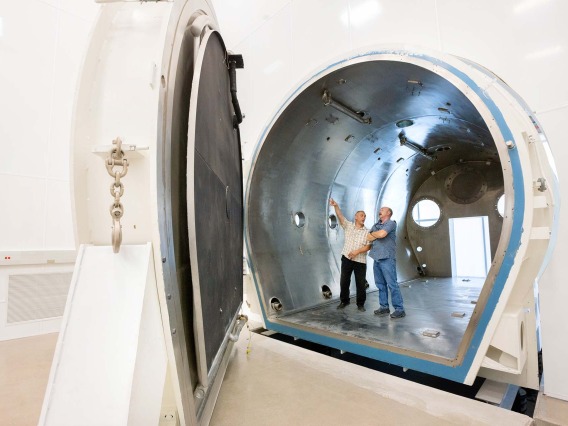 A photograph of Ruben Dominguez, a senior mechanical engineer, and Brian Duffy, a project manager in a thermal vacuum chamber