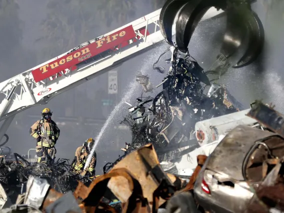 Tucson Fire Department firefighters battle a major fire at a Tucson scrapyard amidst dense smoke in 2022.