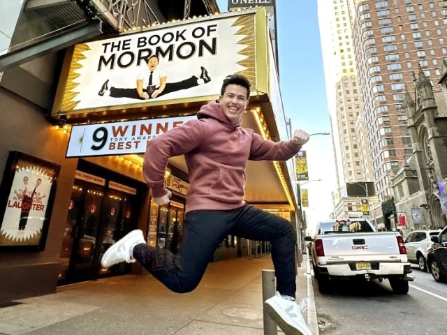 Photo of Alumni Tony Moreno ’21 jumping in front of a theater playing "The Book of Mormon" - the Broadway musical he is a "swing" on.
