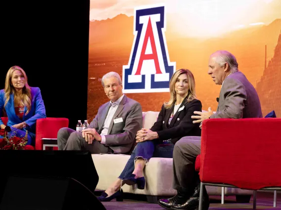 Woman moderates discussion seated on stage with 3 other individuals