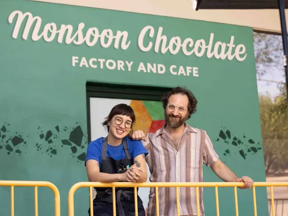 A man and woman pose in front of a storefront 