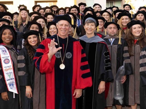 A group of smiling individuals pose in graduation garb