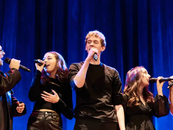 Group of vocalists sings into microphone in acapella performance