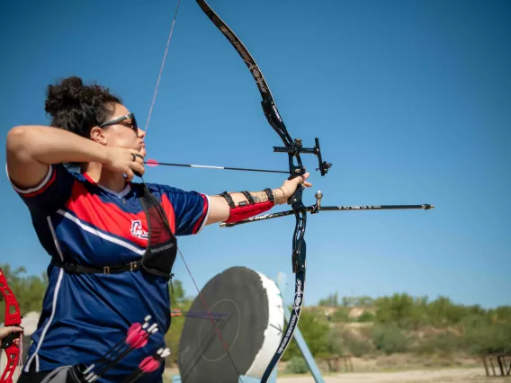 Woman draws a bow against a blue sky