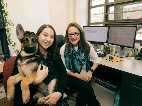 Two researchers pose with Hendrix the German shepherd.