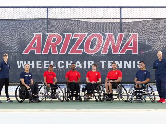 A photograph of six individuals in wheelchairs and two others standing representing the wheelchair tennis program