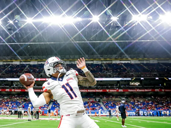 A football player passes the ball in a well lit stadium 