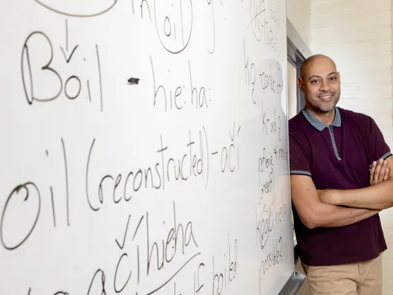 Corey Roberts with his arms crossed smiling next to a white board