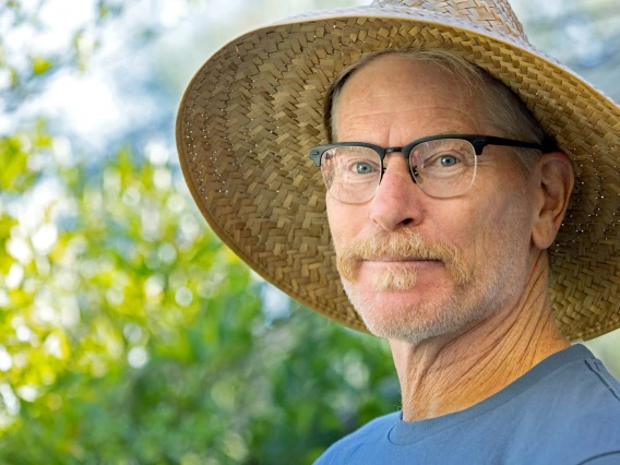 Lancaster looking at the camera, wearing a hat, in the garden 