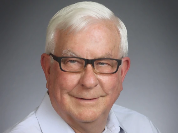 Alan smiling, wearing a white shirt and black glasses 