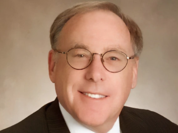 Cecil smiling while wearing a black suit and a gray tie 