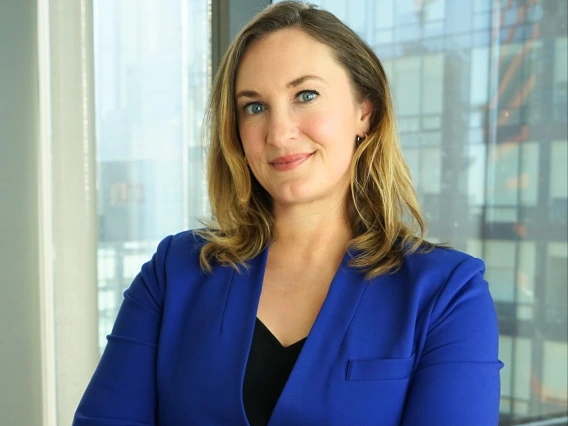 Mary Foote smiling, with her arms crossed, wearing a dark blue blazer and a black shirt 