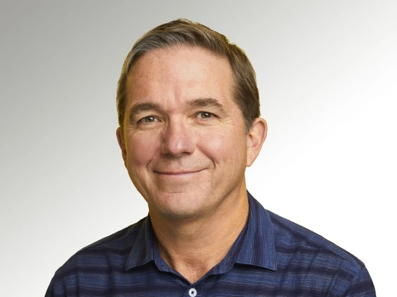 Jerry smiling, wearing a black and blue striped polo 