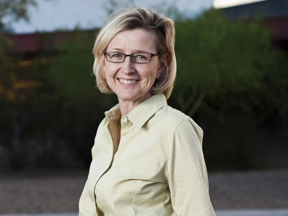 Robin sitting down and smiling, wearing a light-yellow button-up top and gray bottoms 