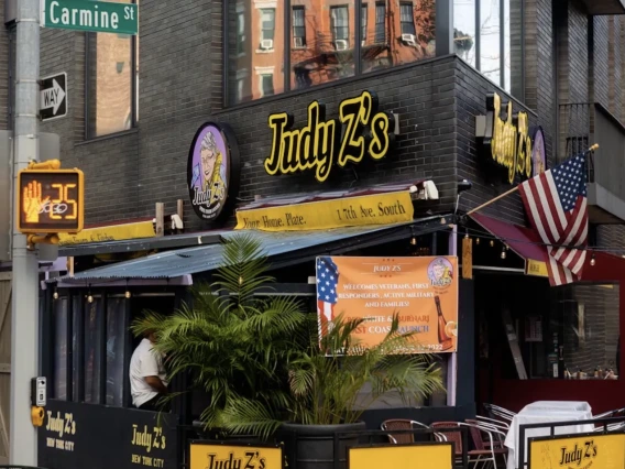 A corner shot of a restaurant with street signs and lights surrounding it