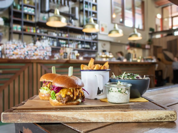 An image of two cheeseburgers fries, dipping sauce and a salad on a wood tray at a upscale burger resturant.