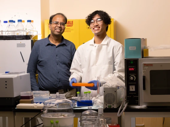 Abhijit Date and Tom Pham smiling and working in the lab. 
