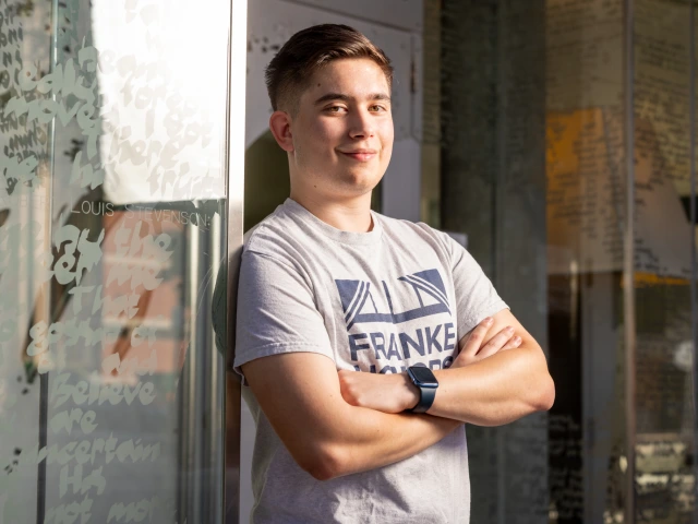 A photo of Tadeusz Borowski with his arms crossed, outside the Árbol de la Vida dorm, where he is a resident assistant