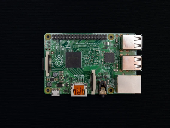 An image of the Raspbery Pi computer that is the size of a credit card. The Raspbery Pi has a forest green base with a typical computer circuit board visible on top.