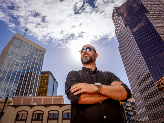 An image of a man wearing sunglasses with his arms crossed in downtown Tucson.