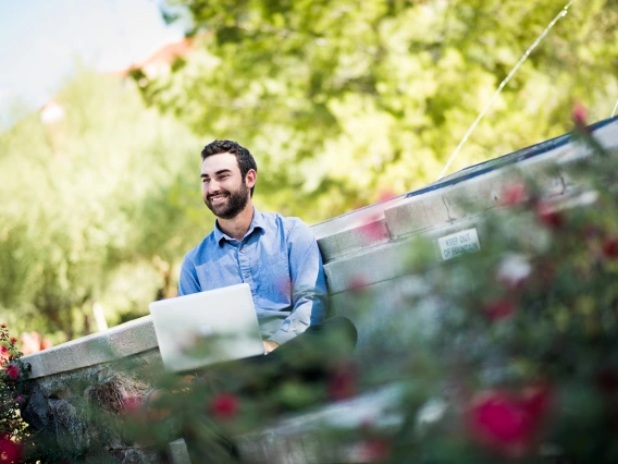 Student on laptop at Old Main Fountain