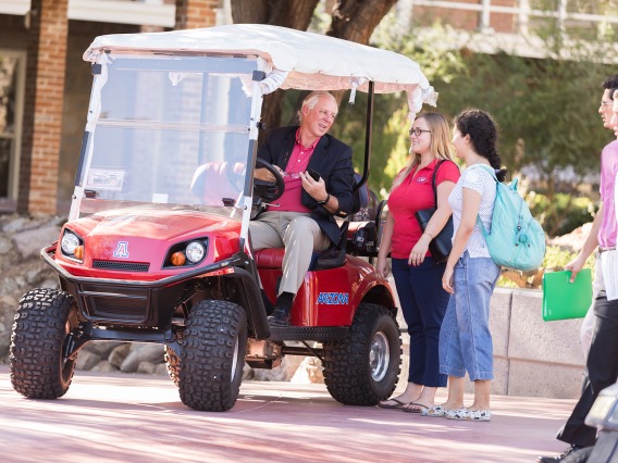 President Robbins with students in golf cart