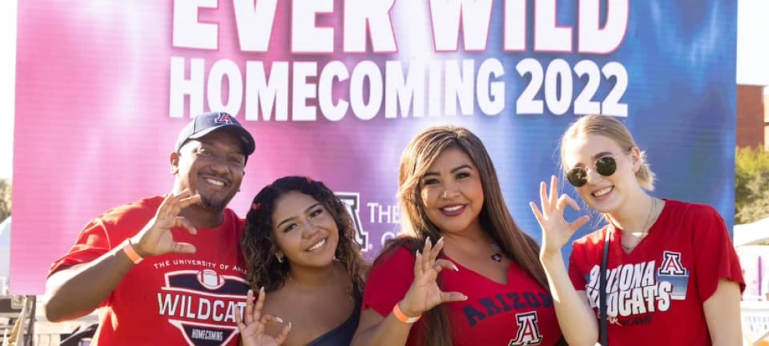 Group posing in front of Homecoming sign