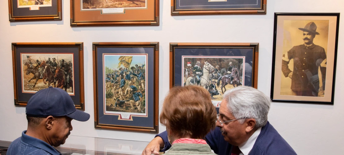 A photograph of an exhibit filled with photos and paintings with guests learning at the African American Museum of Southern Arizona.