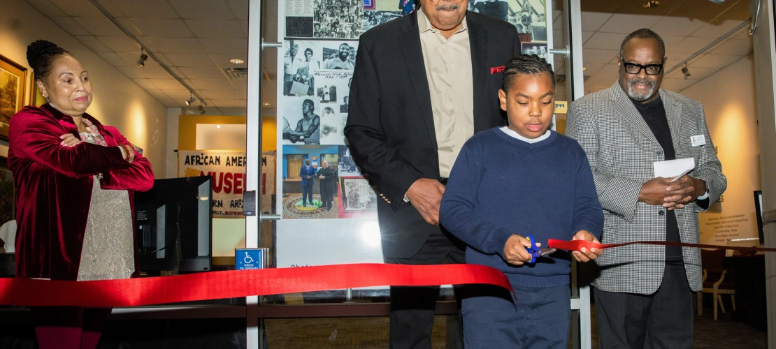 A photograph of a boy cutting ribbon during African American Museum of Southern Arizona opening