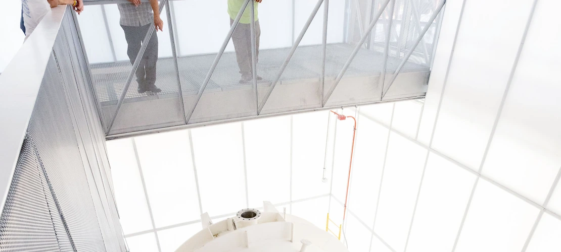A photograph of four people pointing and looking into the chamber 