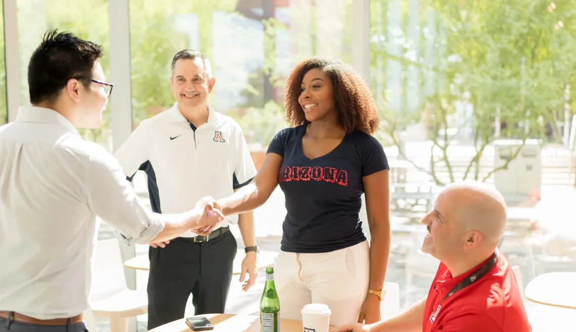 Four people smiling while they shake hands.