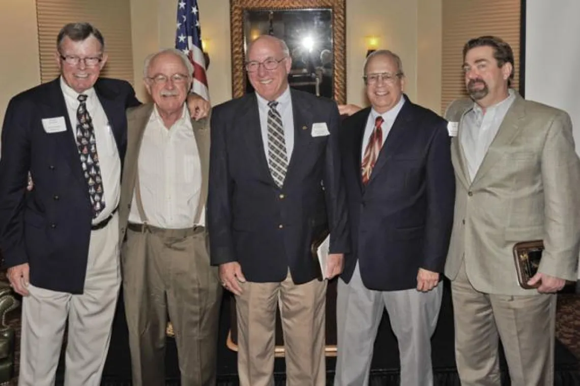 Group of older men in suits hugging