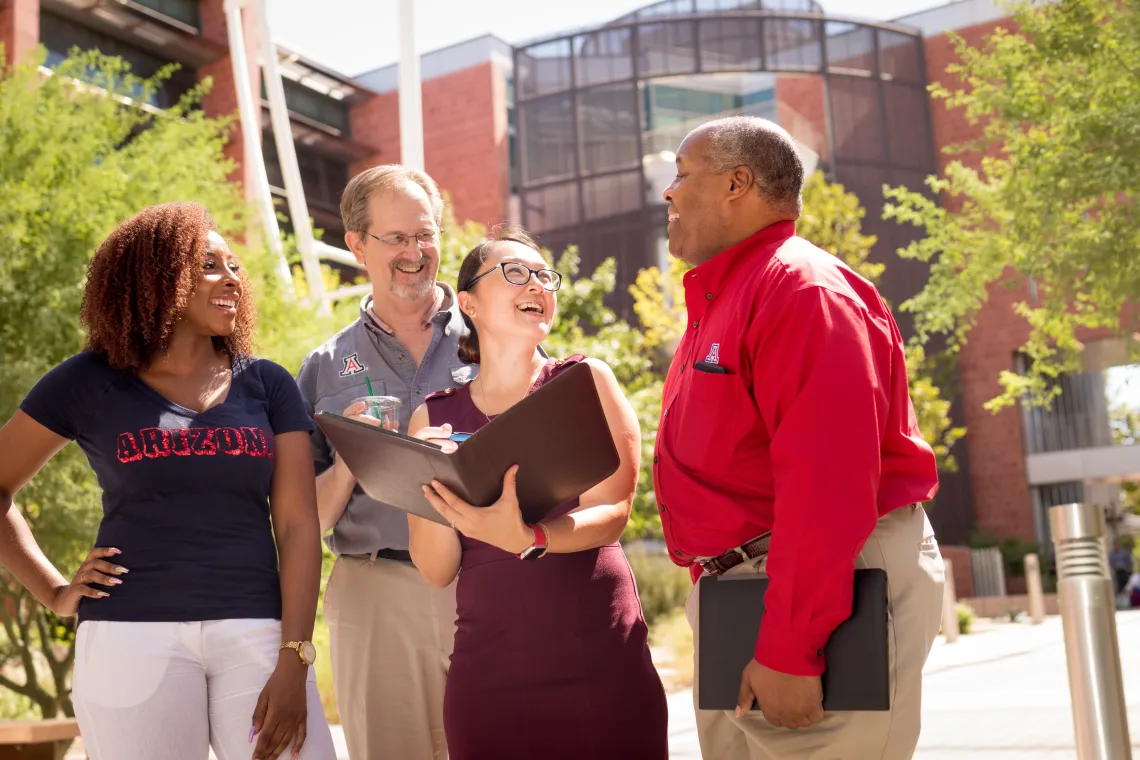 A group of 4 people standing and laughing.