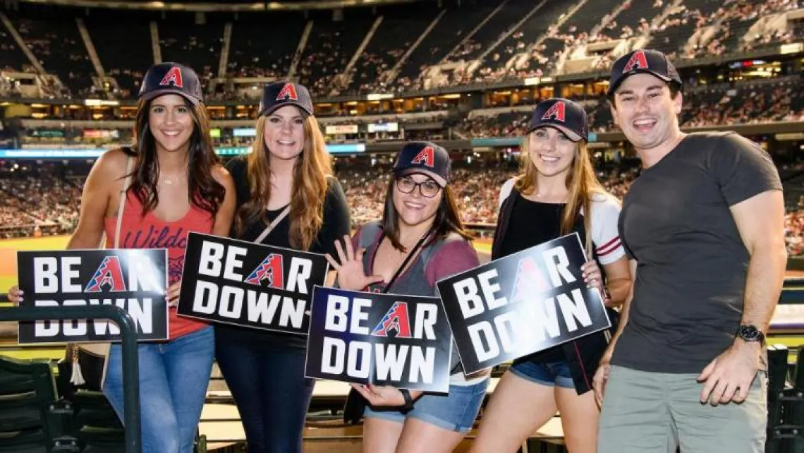 Group of people holding Bear Down signs at baseball field