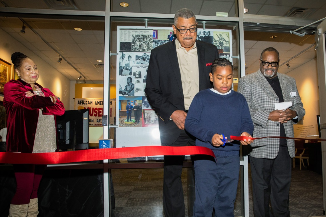 A photograph of a boy cutting ribbon during African American Museum of Southern Arizona opening