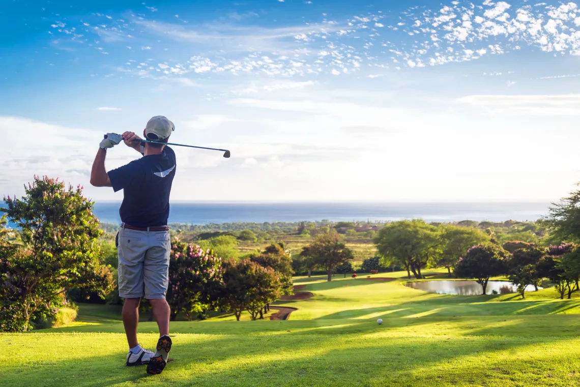 A photograph of a man hitting a golf ball