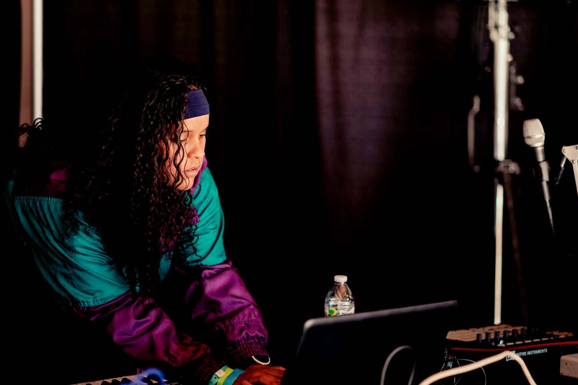 A photograph of a woman working on a computer at a music set.